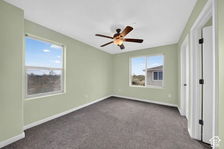 Room featuring neutral wall tones, wall-to-wall carpeting, dual-pane windows, and a ceiling fan with integrated lighting