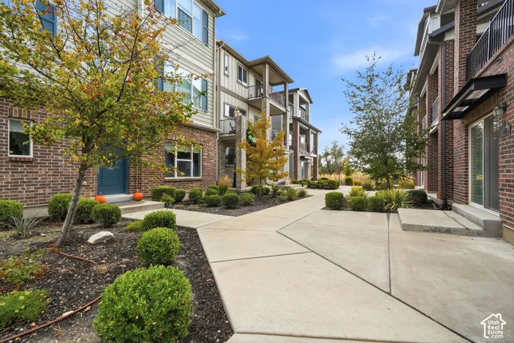 Multi-story exterior featuring brick veneer and horizontal siding, concrete walkways, covered balcony structures, and professional landscaping