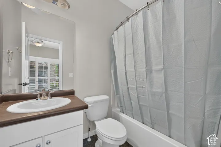 Vanity featuring a wood-finish countertop with a drop-in oval basin, white cabinetry, polished chrome fixtures, a full-height mirror, and a porcelain tub-and-shower combination