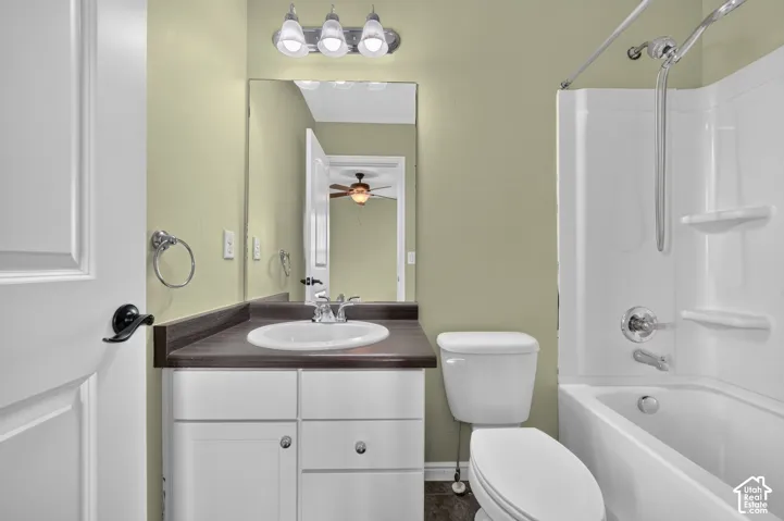 En-suite Bathroom featuring a vanity with a dark-finish countertop, white cabinetry, a full-width mirror, polished chrome fixtures, and a white tub-shower combination