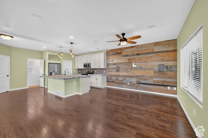 Kitchen featuring white cabinetry, wood-finish flooring, a kitchen island, a reclaimed wood-style accent wall, and recessed lighting