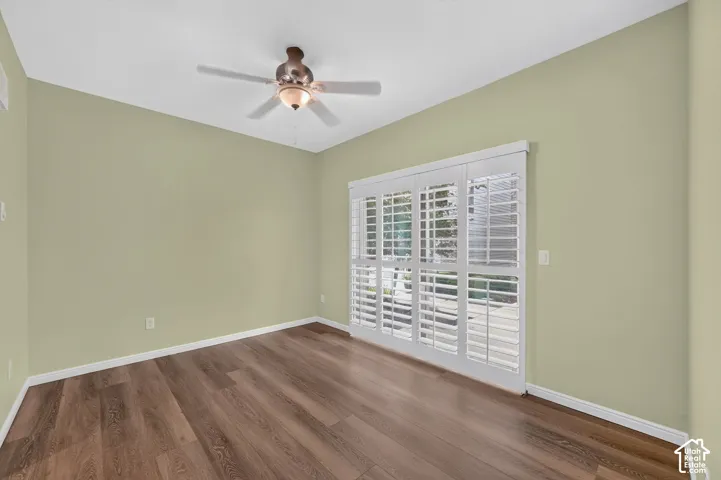 Wood-finish flooring, white plantation shutters, multi-panel sliding glass door, and a ceiling fan with integrated light fixture