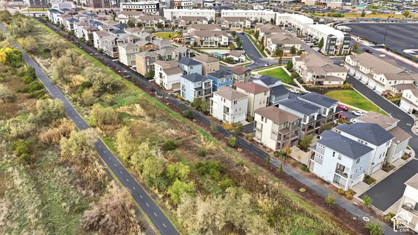 Aerial perspective of a multi-unit residential community featuring paved walkways, extensive green space, and proximity to a paved recreational trail