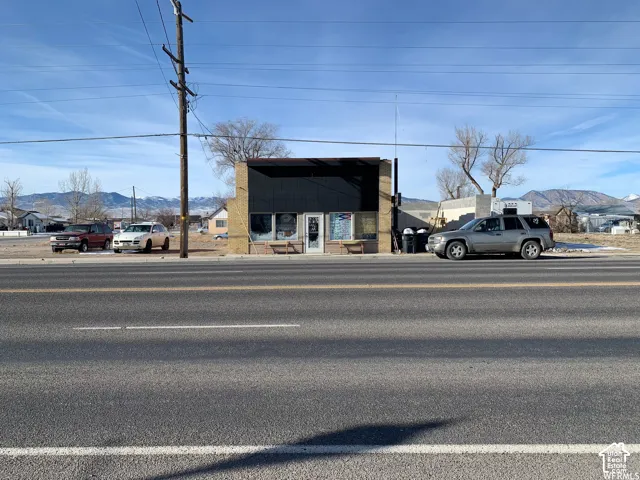 Commercial structure featuring a tan brick exterior, glass display windows, a central glass-panel door, and mountain surroundings
