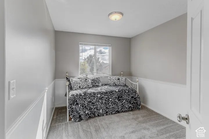 Neutral-toned room featuring wall-to-wall carpeting, chair rail molding, and a central ceiling light fixture
