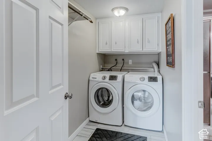 Laundry area featuring white shaker-style wall cabinets, a metal hanging rod, and tile flooring