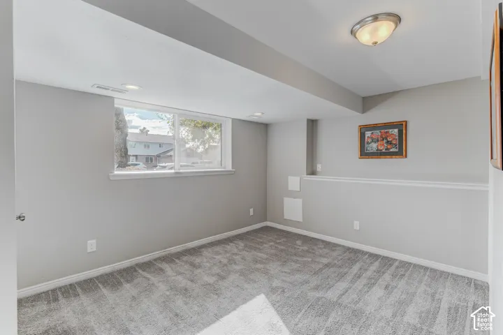 Neutral interior space featuring wall-to-wall carpeting, horizontal sliding window, and flush-mount ceiling lighting