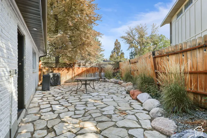 Flagstone patio featuring a wood-panel fence, stone garden border, and mature trees