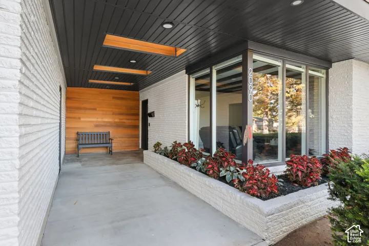 Covered entryway featuring painted brick walls, natural wood-paneled accents, integrated wood-framed skylights, and a built-in masonry planter box