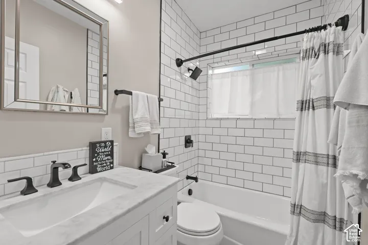 White vanity with a stone-top integrated sink, subway tile shower surround, matte black plumbing fixtures, and a framed mirror