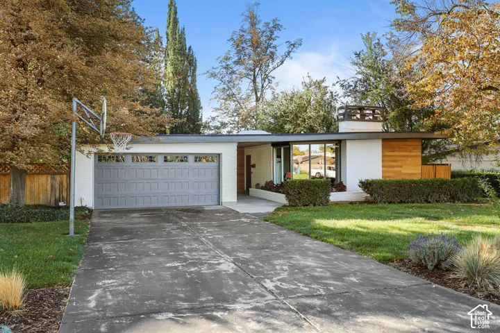 Mid-century modern exterior featuring white masonry, horizontal wood siding, a flat roofline, and an attached multi-car garage