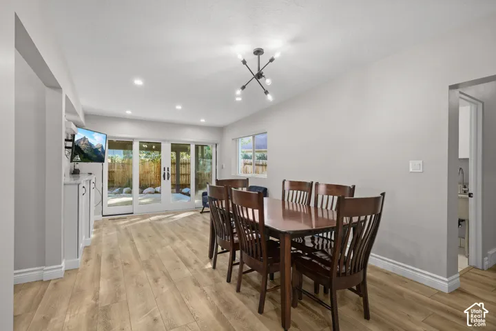 Dining area featuring wood-finish flooring, a multi-arm industrial-style chandelier, recessed lighting, built-in cabinetry, and multi-panel sliding glass doors