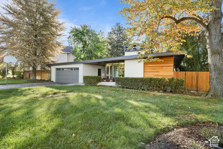 Mid-century modern exterior featuring horizontal wood siding, a flat roofline, floor-to-ceiling windows, and an attached two-car garage