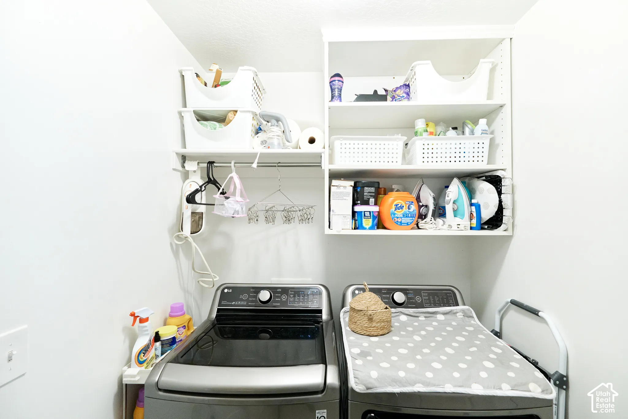 Laundry space featuring white custom wall-mounted shelving and a dedicated metal clothing rod