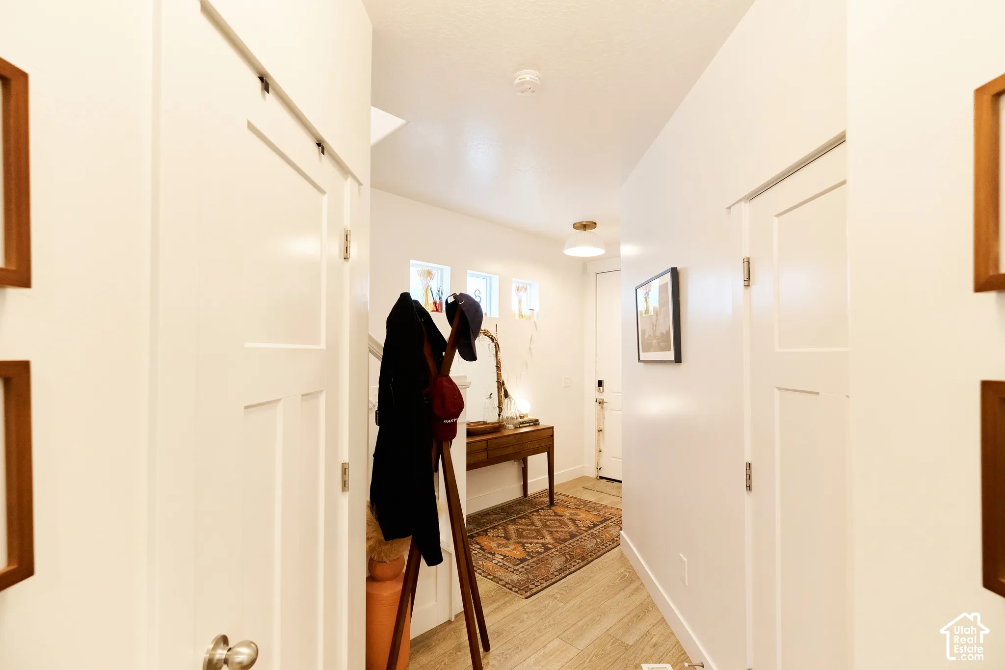 Entryway featuring wood-finish flooring, white shaker-style doors, trio of clerestory windows, and a flush-mount light fixture