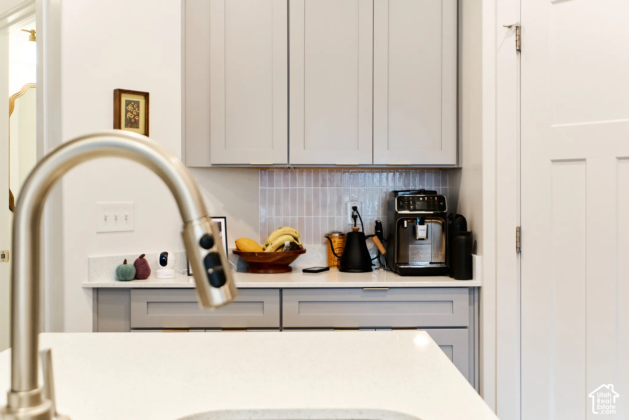 Shaker-style grey cabinetry, quartz countertops, vertical tile backsplash, and a high-arc pull-down faucet