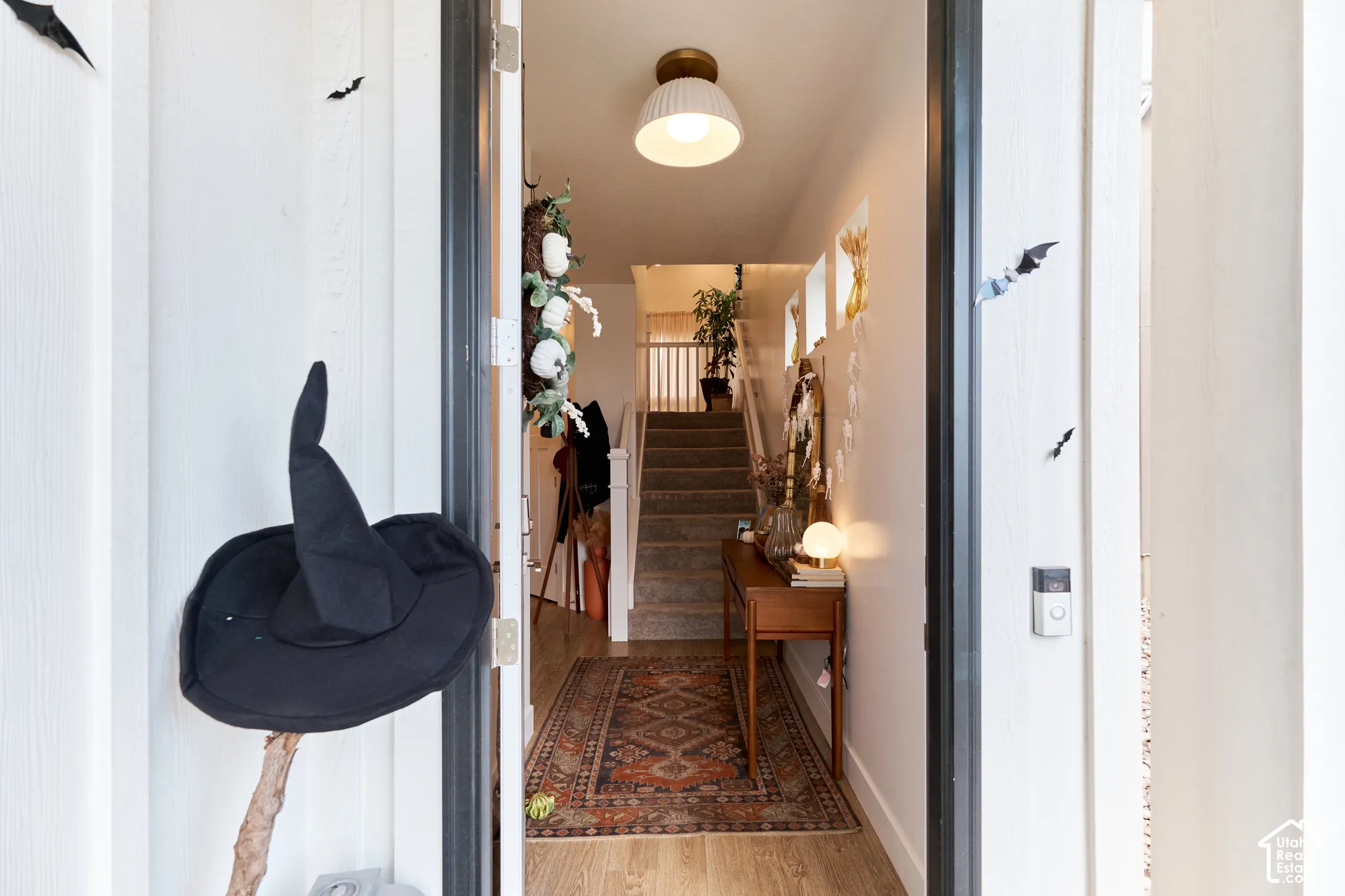 Foyer entrance featuring wood-finish flooring, a semi-flush mount dome lighting fixture, and a staircase with a white handrail