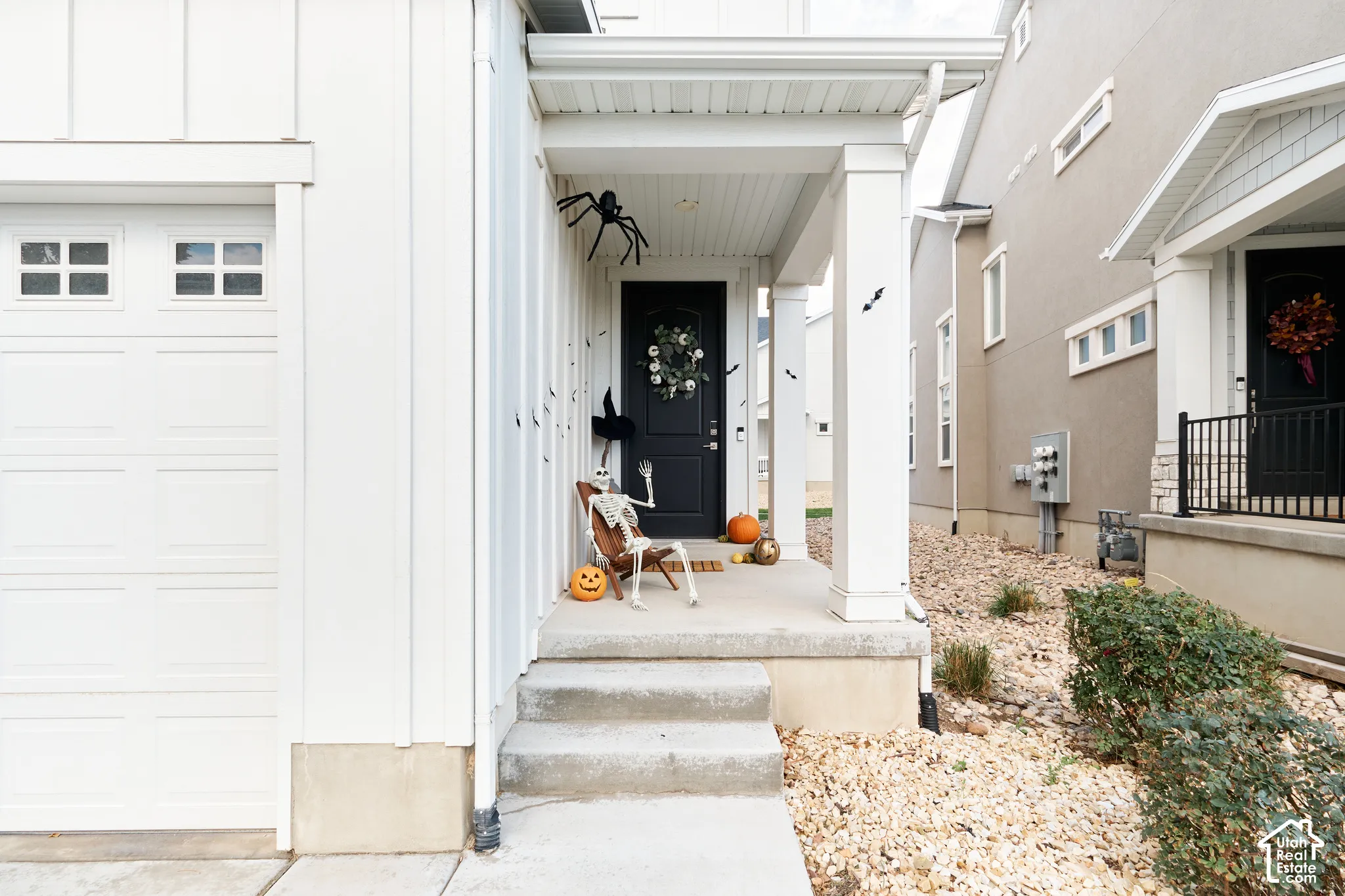 Board-and-batten siding exterior featuring a covered front porch with square columns, concrete steps, and a dark-toned entry door