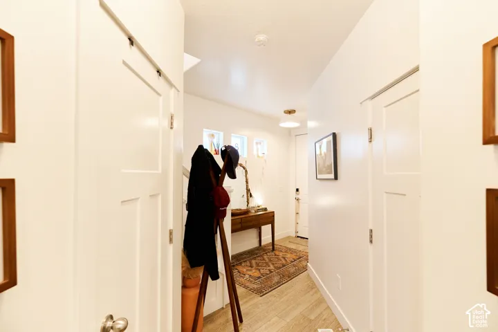 Entryway featuring wood-finish flooring, white shaker-style doors, trio of clerestory windows, and a flush-mount light fixture