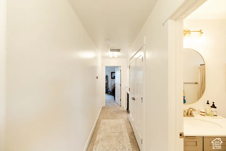 Hallway featuring white walls, multi-panel interior doors, and textured carpet flooring