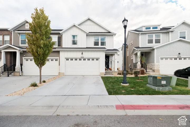 Two-story residence featuring white vertical siding, an attached two-car garage, concrete driveway, and a covered front entry porch