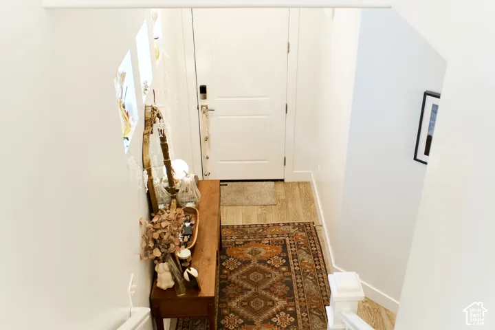 Entryway featuring a solid panel front door, wood-finish flooring, and integrated wall niches