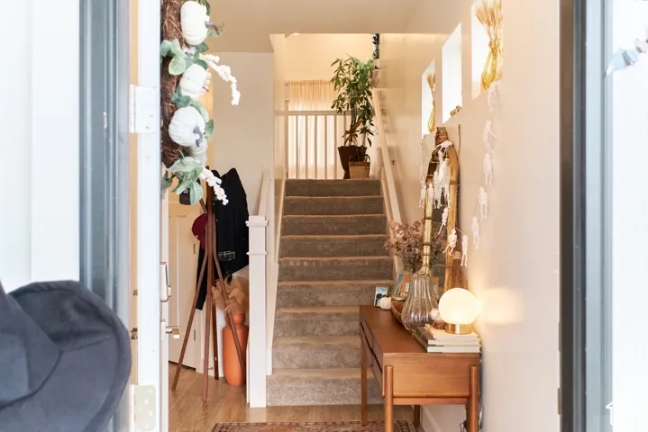 Entryway featuring wood-finish flooring, a carpeted staircase with white balusters, and integrated recessed wall niches