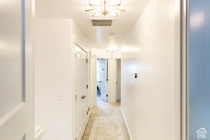 Hallway featuring multi-panel interior doors, geometric star-patterned flush-mount lighting, and neutral carpeting