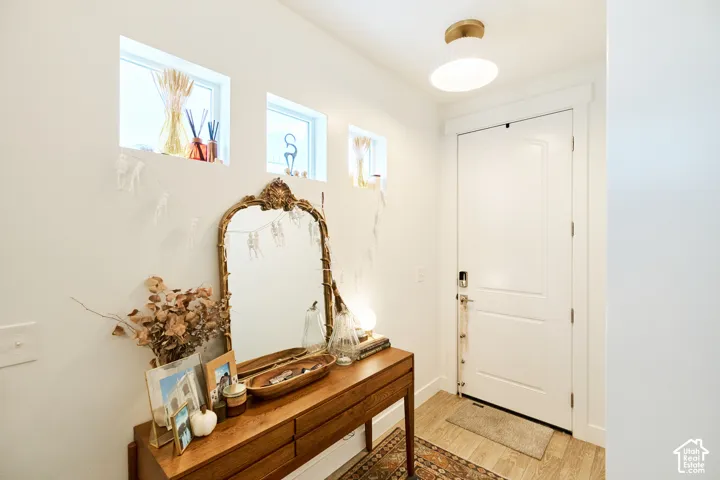 Entryway featuring wood-finish flooring, three transom-style windows, and a flush-mount light fixture with gold-tone hardware