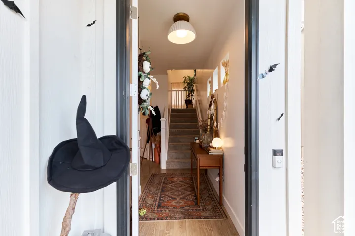 Foyer entrance featuring wood-finish flooring, a semi-flush mount dome lighting fixture, and a staircase with a white handrail