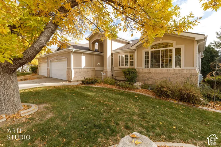 Exterior facade featuring stone and stucco siding, a covered entryway, an arched window detail, and a multi-car garage
