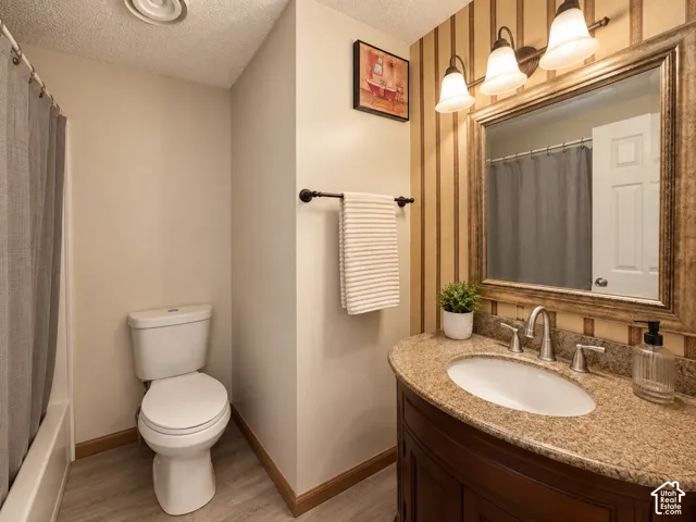 Bathroom vanity featuring a speckled stone-finish countertop, undermount sink, three-light wall-mounted fixture, and a decorative framed mirror