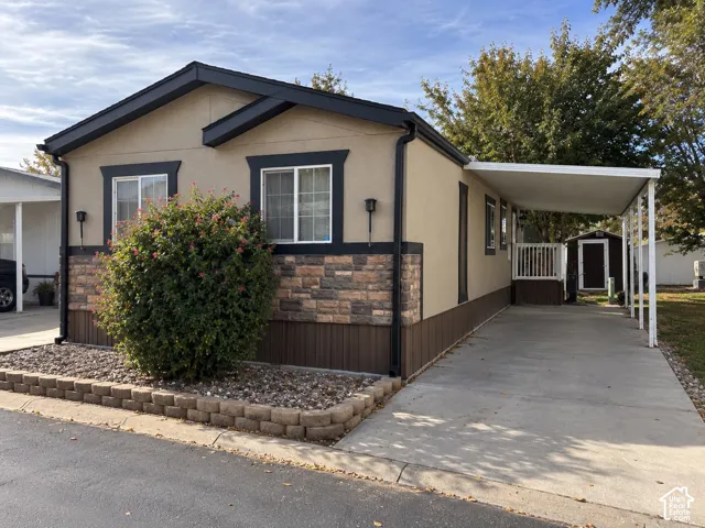 Exterior featuring stone veneer accents, multi-tone siding, a concrete driveway, a covered carport, and a raised wooden deck
