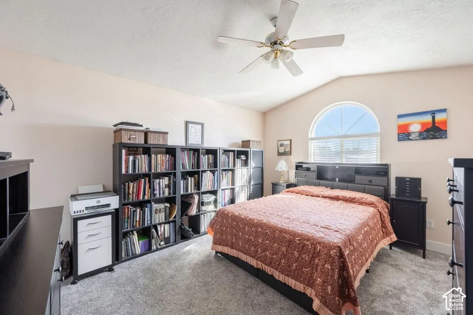 Vaulted ceilings featuring a central overhead fan and a prominent arched window