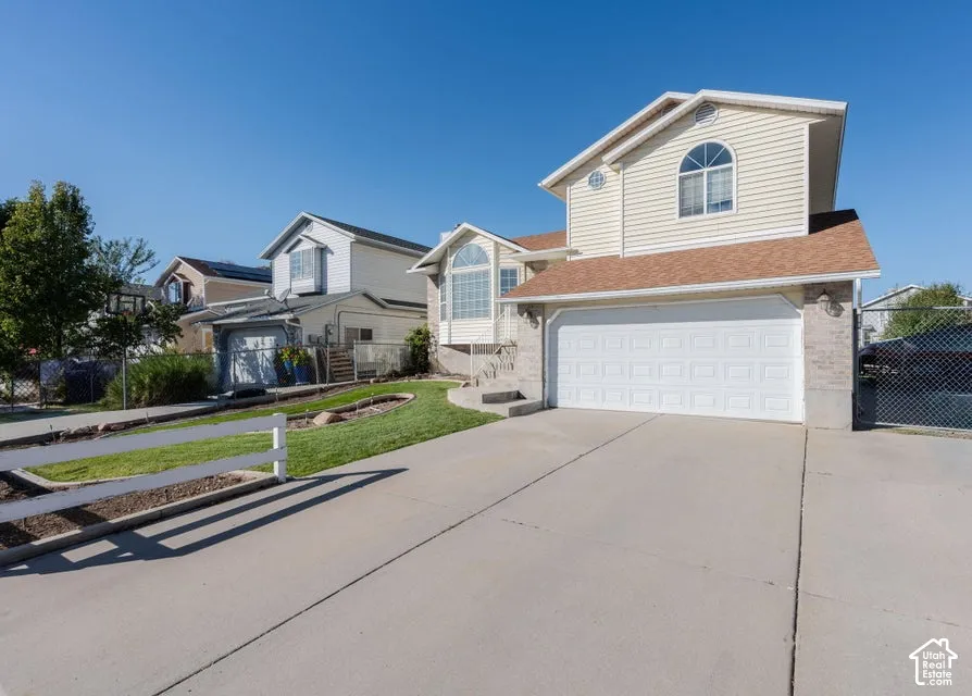 Two-story exterior featuring light-toned horizontal siding, a multi-gabled roofline, arched windows, and an attached two-car garage with a concrete driveway