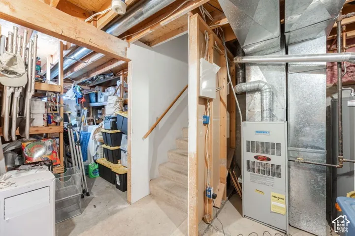 Exposed ceiling joists, metal ductwork, and utility room featuring a concrete floor, built-in shelving, and a mechanical furnace