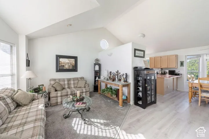 Vaulted ceilings, a partial dividing wall, wood-finish flooring, and a multi-tier kitchen counter