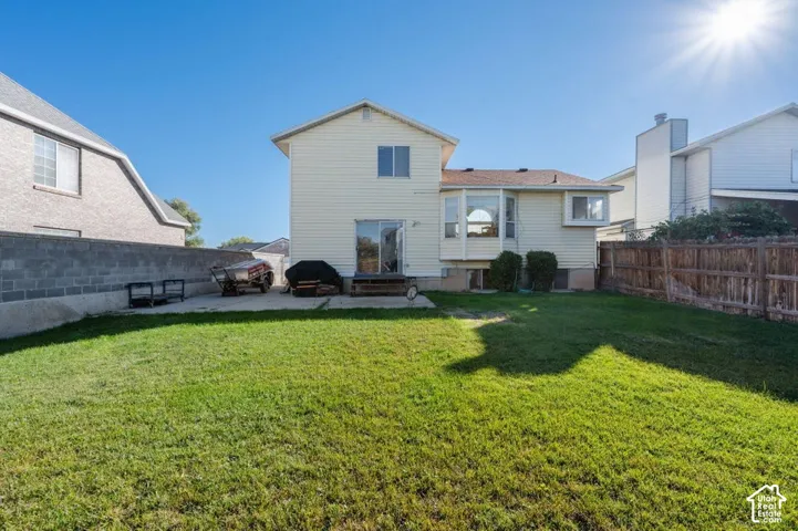 Rear exterior featuring vinyl siding, concrete patio, bay window, and a fenced backyard