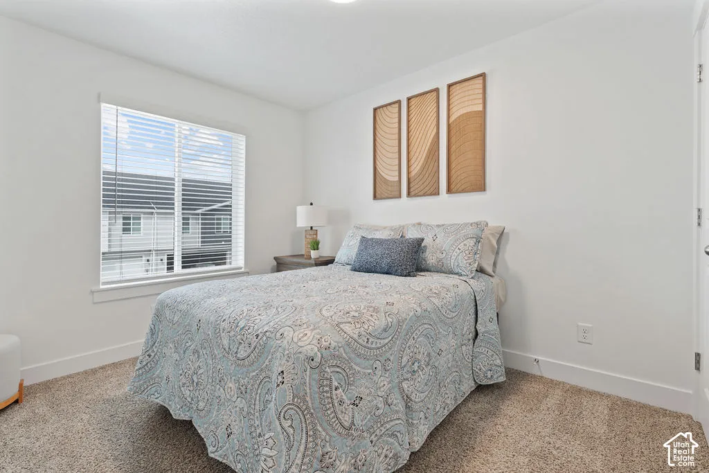 Neutral-toned carpeting and bright white walls featuring a single large window with horizontal blinds