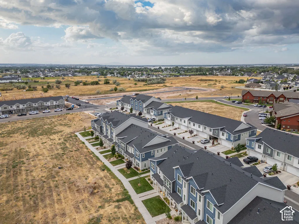 Multi-story residential community featuring dark shingle roofing, blue and neutral siding, attached garage structures, and paved walkways