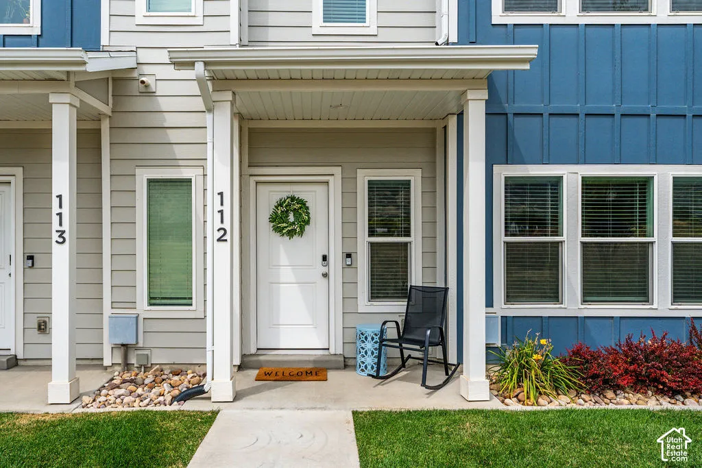 Exterior featuring a covered entryway, lap and vertical board-and-batten siding, concrete porch, and decorative rock landscaping