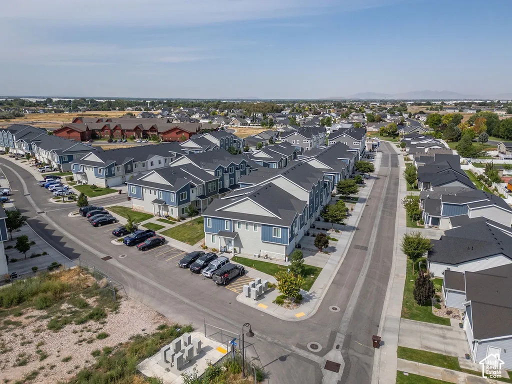 Aerial perspective of a planned community featuring multi-unit residential structures, asphalt roadways, designated parking areas, and mature landscaping