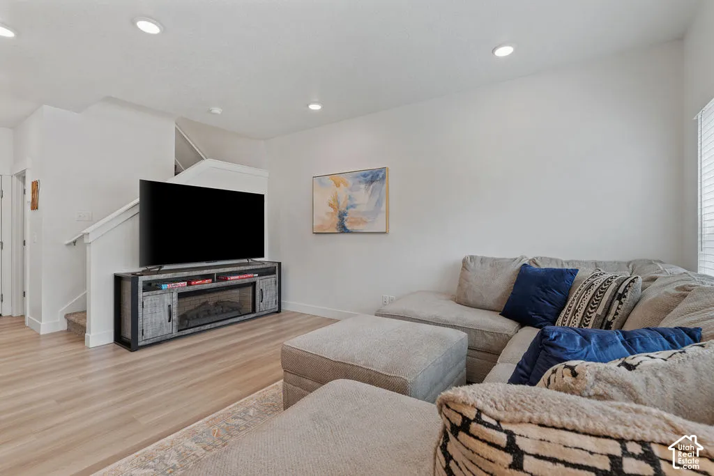 Recessed ceiling lighting, light-tone wood-finish flooring, and white interior walls