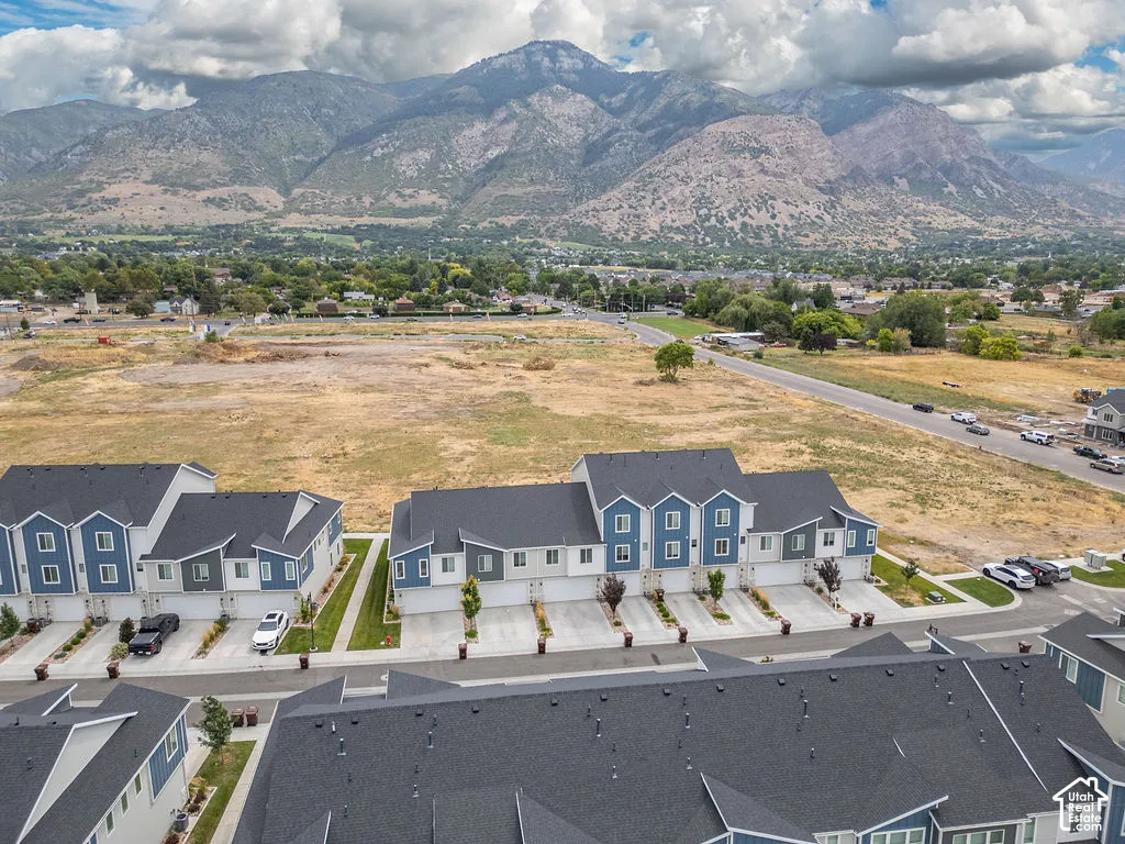 Multi-level townhome exteriors featuring blue-toned siding, dark shingled roofs, concrete driveways, and proximity to expansive mountain ranges