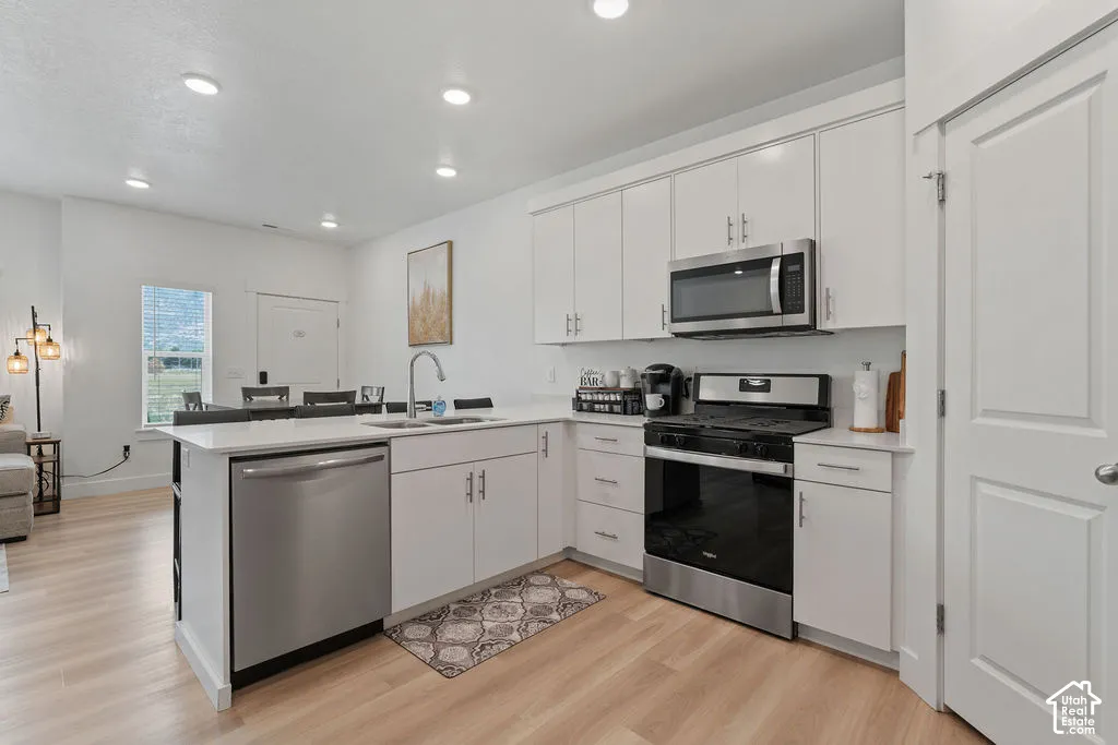 Kitchen featuring white cabinetry, light-toned wood-finish flooring, recessed lighting, quartz countertops, and stainless steel appliances