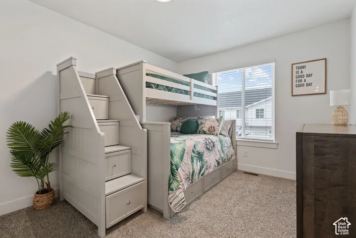 Neutral interior space featuring wall-to-wall carpeting, crisp white wall finish, and a large horizontal window providing natural light