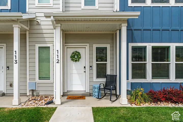 Exterior featuring a covered entryway, lap and vertical board-and-batten siding, concrete porch, and decorative rock landscaping