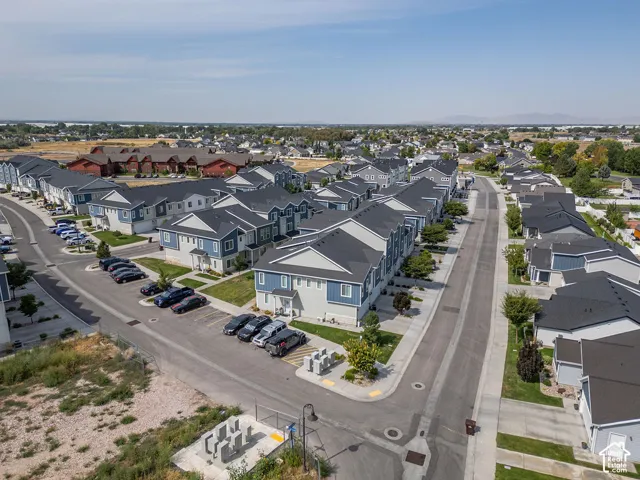 Aerial perspective of a planned community featuring multi-unit residential structures, asphalt roadways, designated parking areas, and mature landscaping