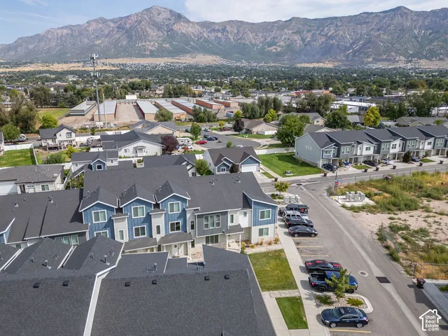 Multi-story residential complex featuring blue vertical siding, stone masonry accents, asphalt shingle roofing, and prominent mountain backdrop
