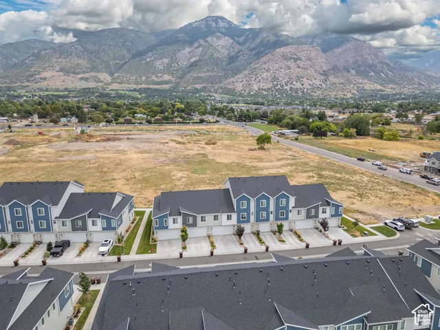 Multi-level townhome exteriors featuring blue-toned siding, dark shingled roofs, concrete driveways, and proximity to expansive mountain ranges